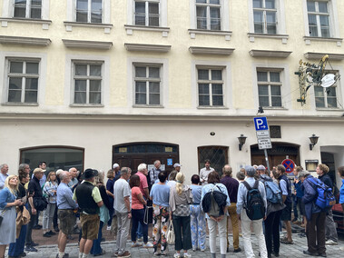 Foto einer größeren Ansammlung von Personen vor einem Stadthaus.